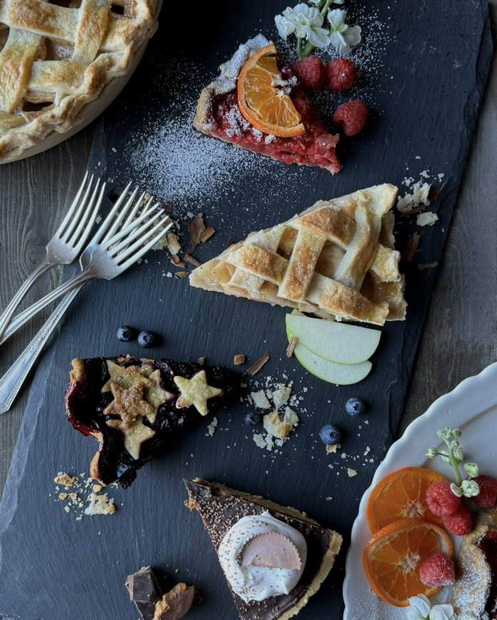 4 Pie Day Recipes Four different slices of pie recipes sit on a black table with two whole pies peaking out of the top left and bottom right corners.