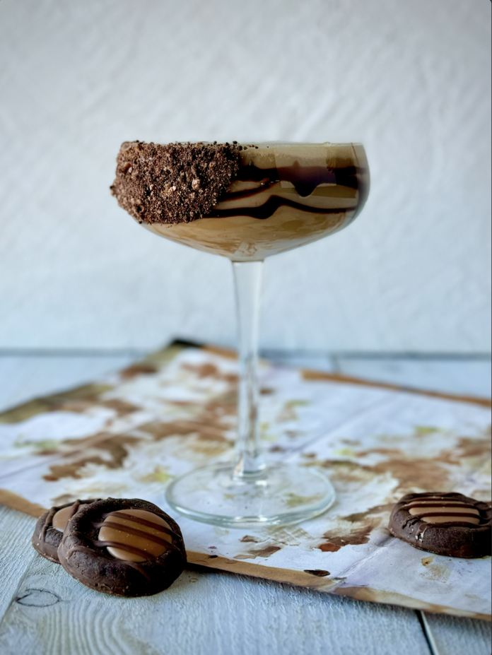 Adventurefuls Cocktail An Adventurefuls® Cocktail is placed in a cocktail glass drizzled with chocolate syrup and rim coated in crushed Adventurefuls® cookies. Three Adventurefuls® cookies sit in front of the glass.