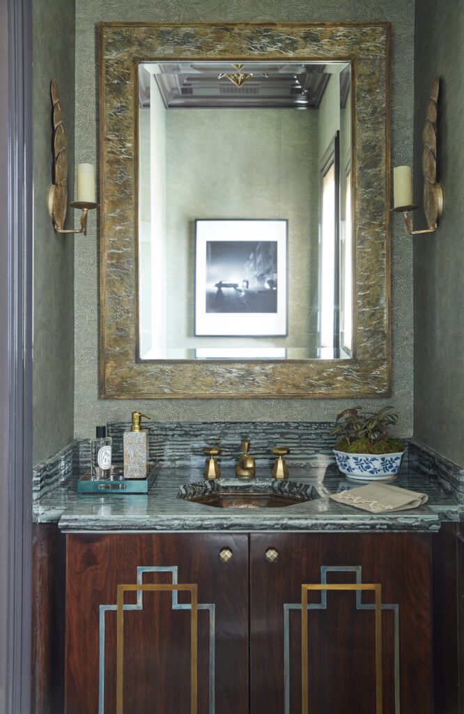 A beautiful jewel box powder room with antique mirror.