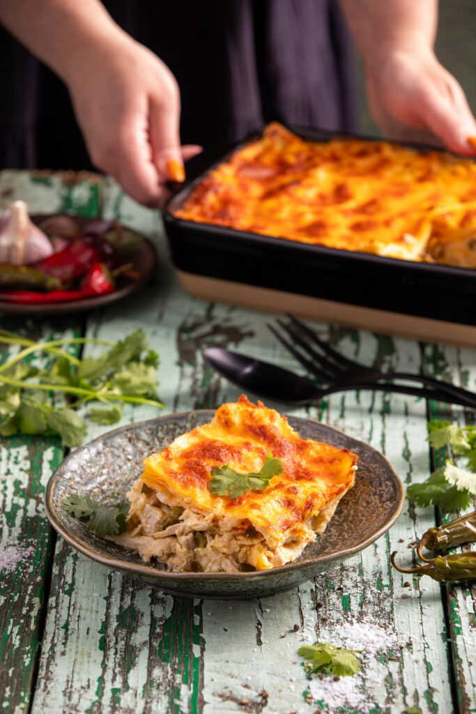 Green Chile Chicken Enchilada Casserole served in a plate which is placed on a wooden surface