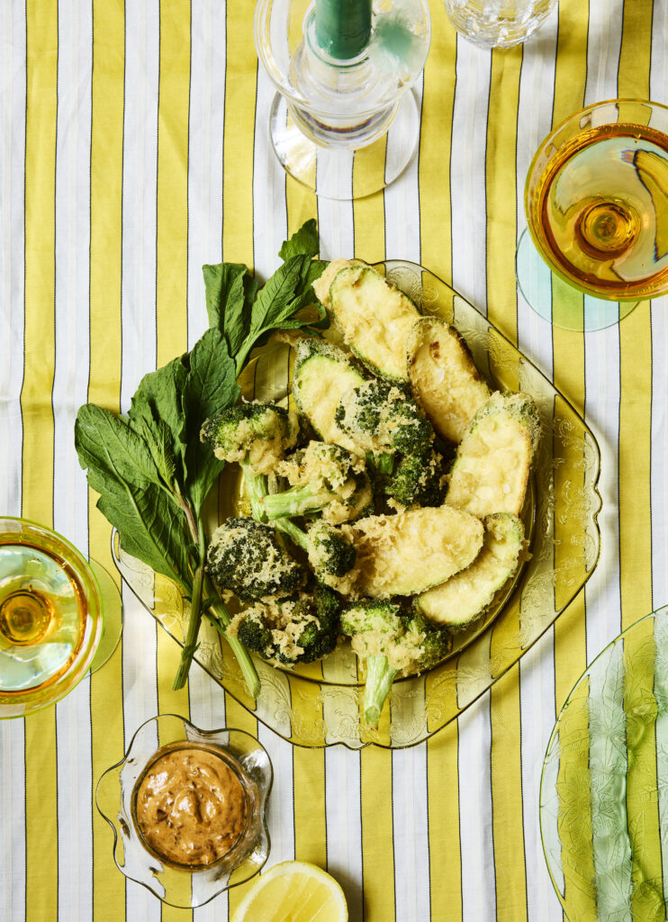 A clear plate holds a meal of tempura made with fresh masa on top of a yellow striped table.