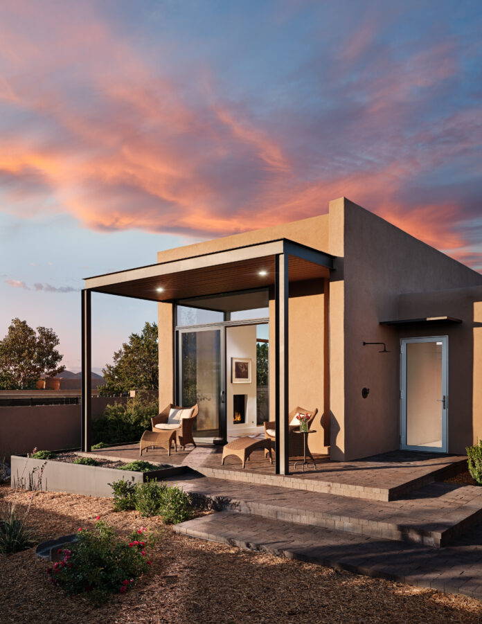 A small rectangular custom design house of Paul and Michael Violante sits below a colorful sunset sky..