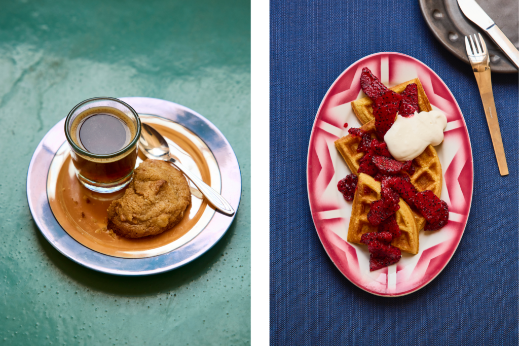 On the left is a photo of a cookie and shot of espresso on a plate that's on a teal table then on the right is a red and white plate of waffles topped with berries and whipped cream on a blue table.