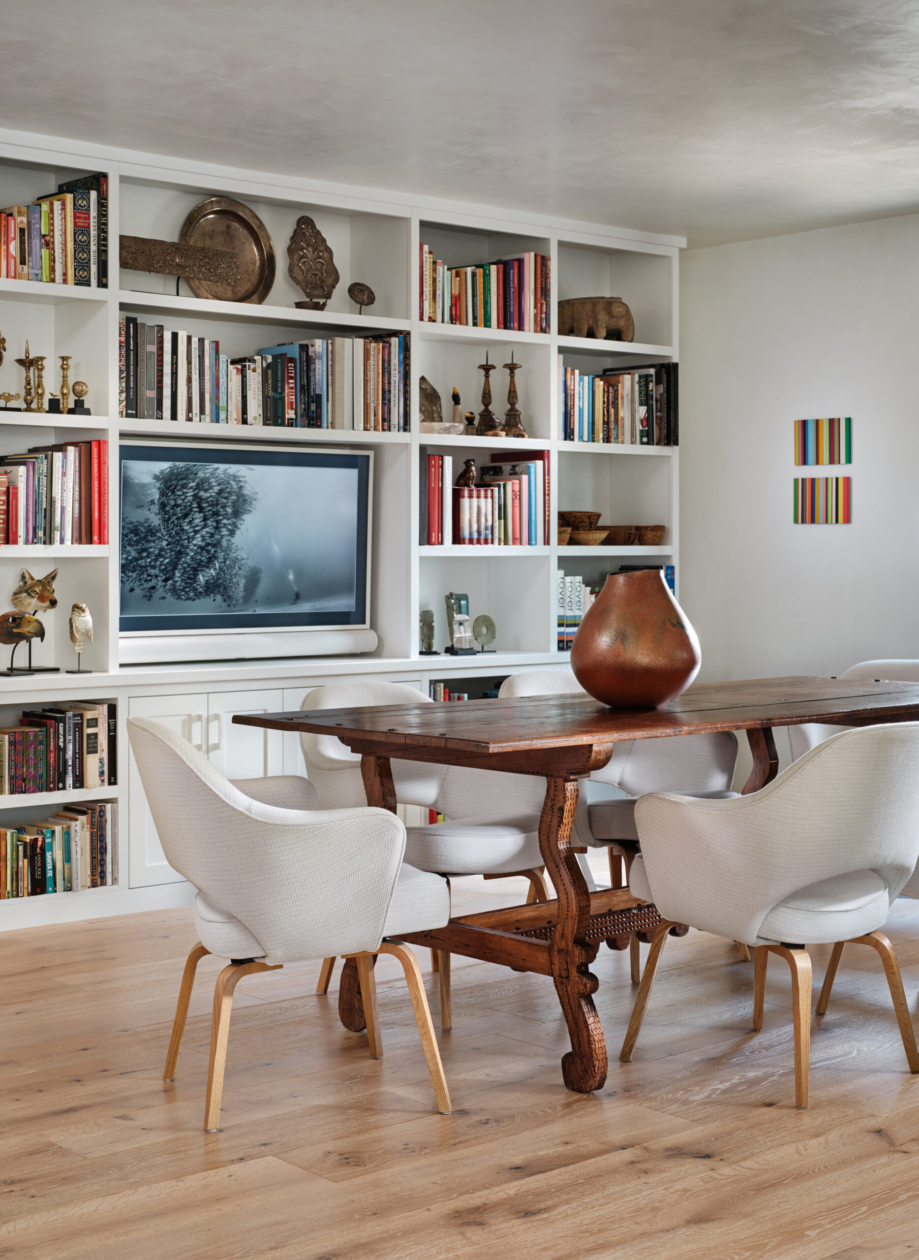 A television screen finds a home in the bookshelves that anchor the dining zone.