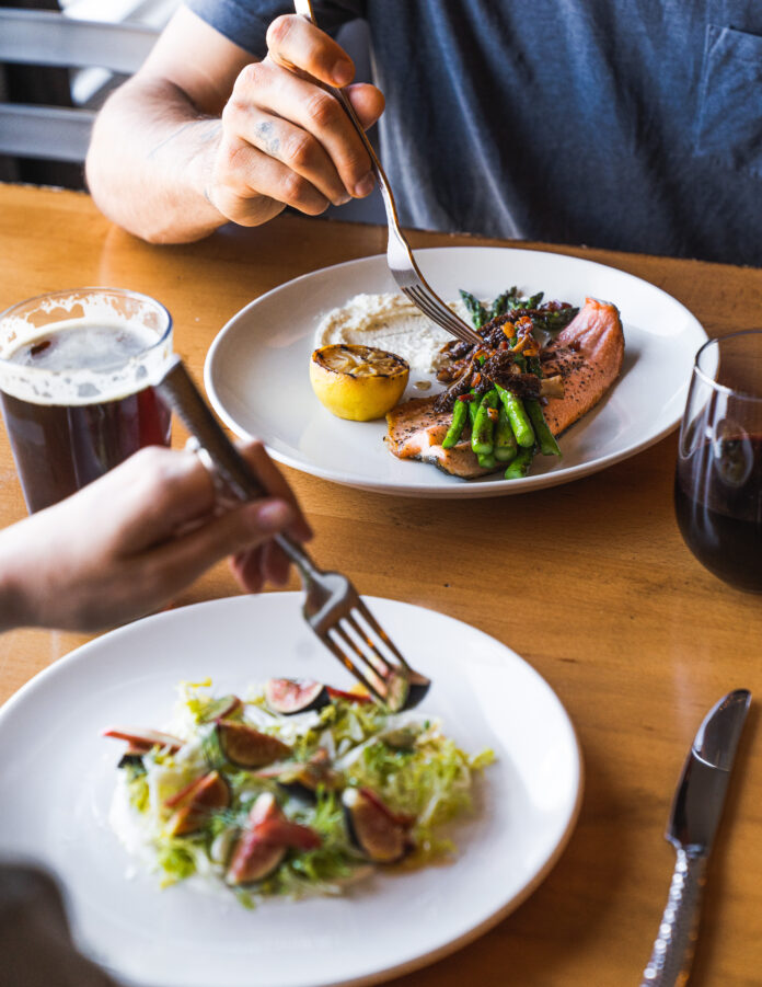 Two people poke their forks at food on white plates at a table in New Mexico.