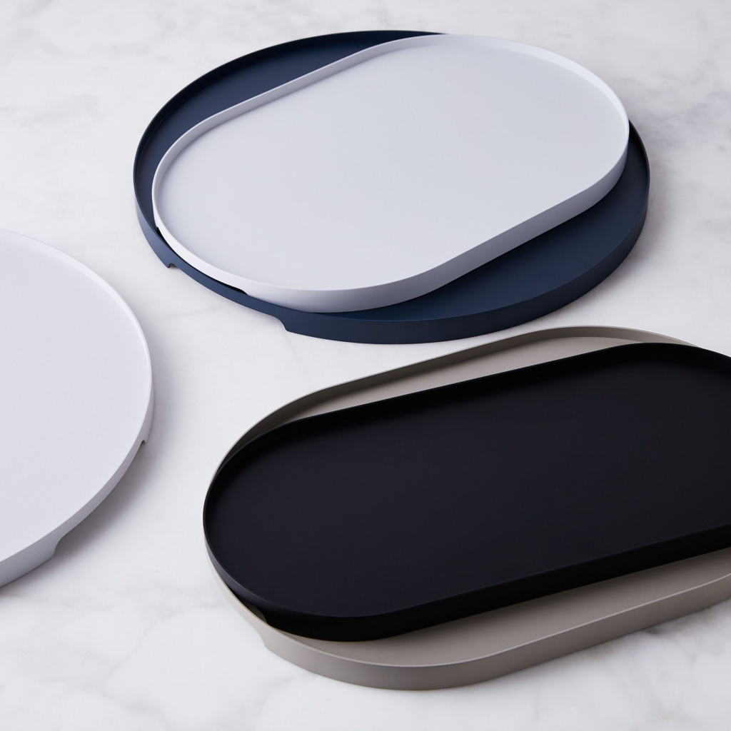 A variety of white and black serving trays scattered over a marble counter.
