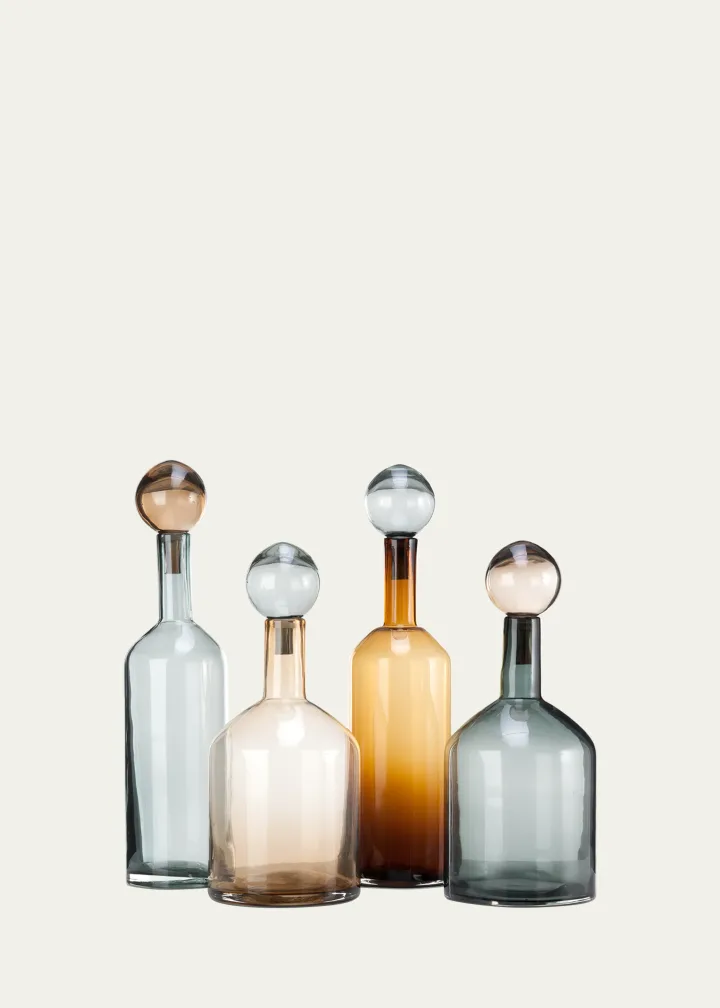A four piece barware bottle set from Pols Potten in the colors blue, orange, and pink sit on a blank background.