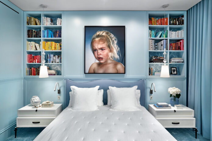 A pale blue bedroom wall, with built in book shelves on either side fo the walls, and a white bed in the middle. favorite colors 2024