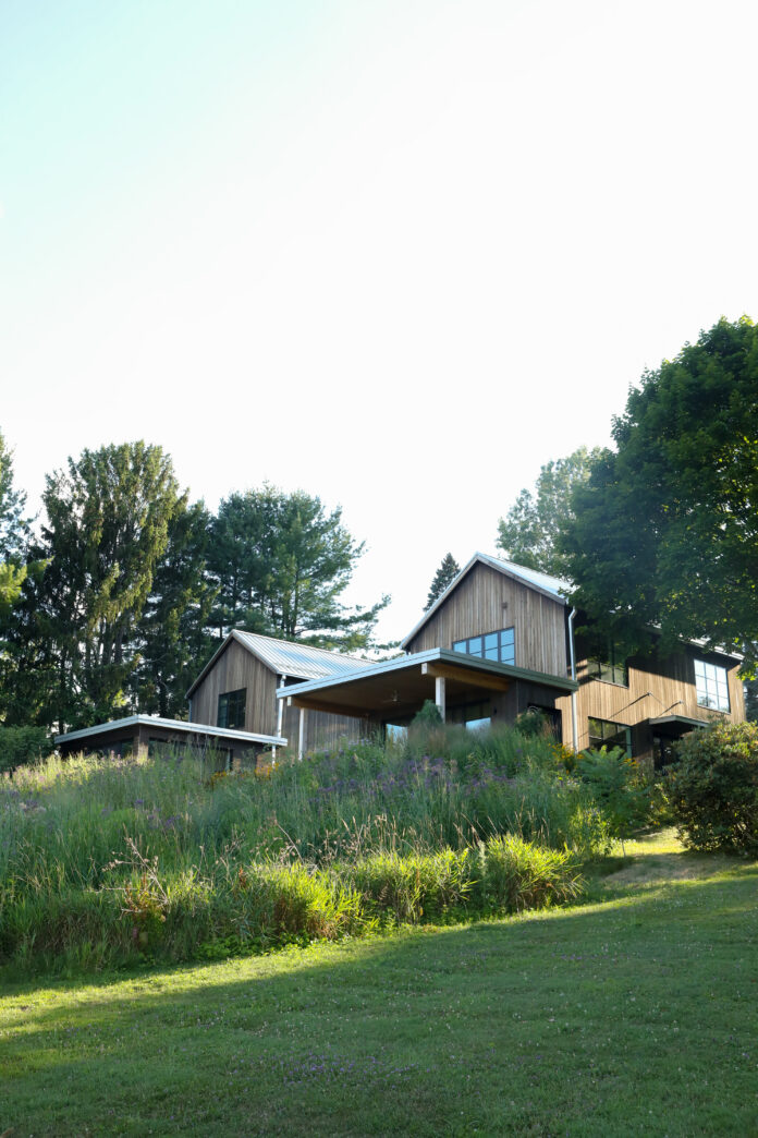 The outside of a Chautauqua Lake house surrounded by tall green grass and trees.