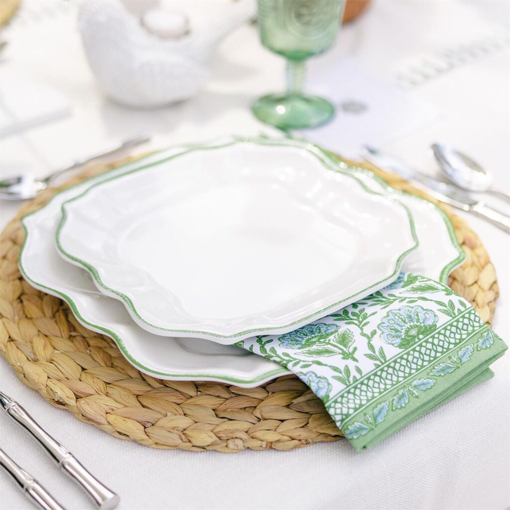 Two white plates with a mint green napkin in between them and a green opaque glass nearby.