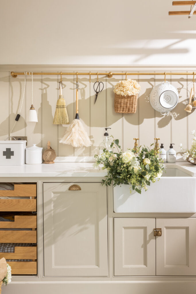 A neutral colored kitchen with beige cabinets, a white countertop, and various wicker products hanging above the counter.