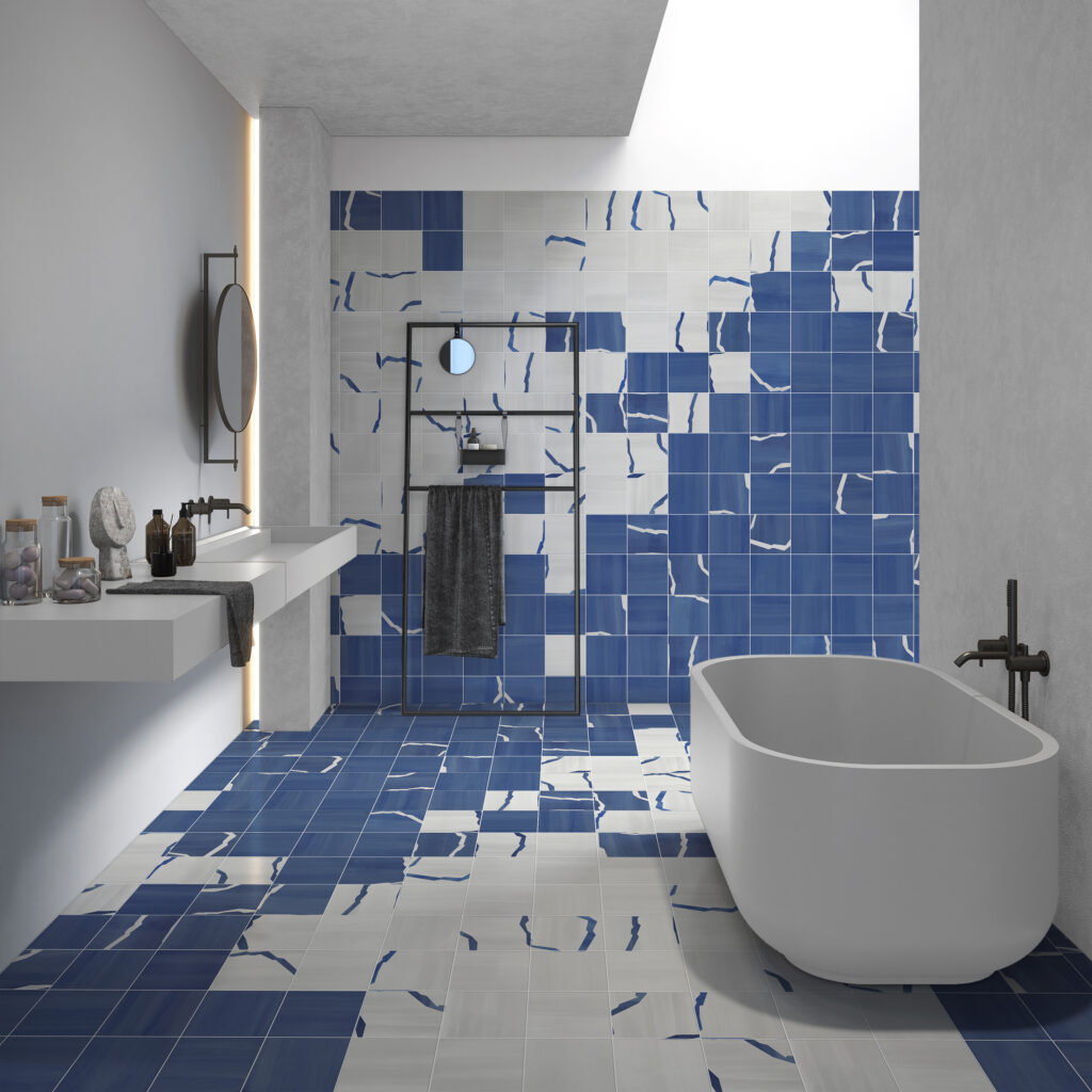A blue and white tiled bathroom with a white bathtub on the right and white sink on the left.
