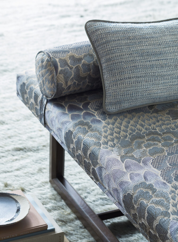 A blue snakeskin pattern couch against a light colored floor with a matching pillow on the couch.
