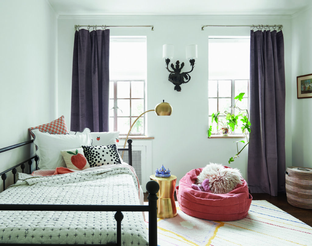 A bedroom with two windows has a daybed in it and pink bean bag chair sitting near by, decorated by Studio Lithe.