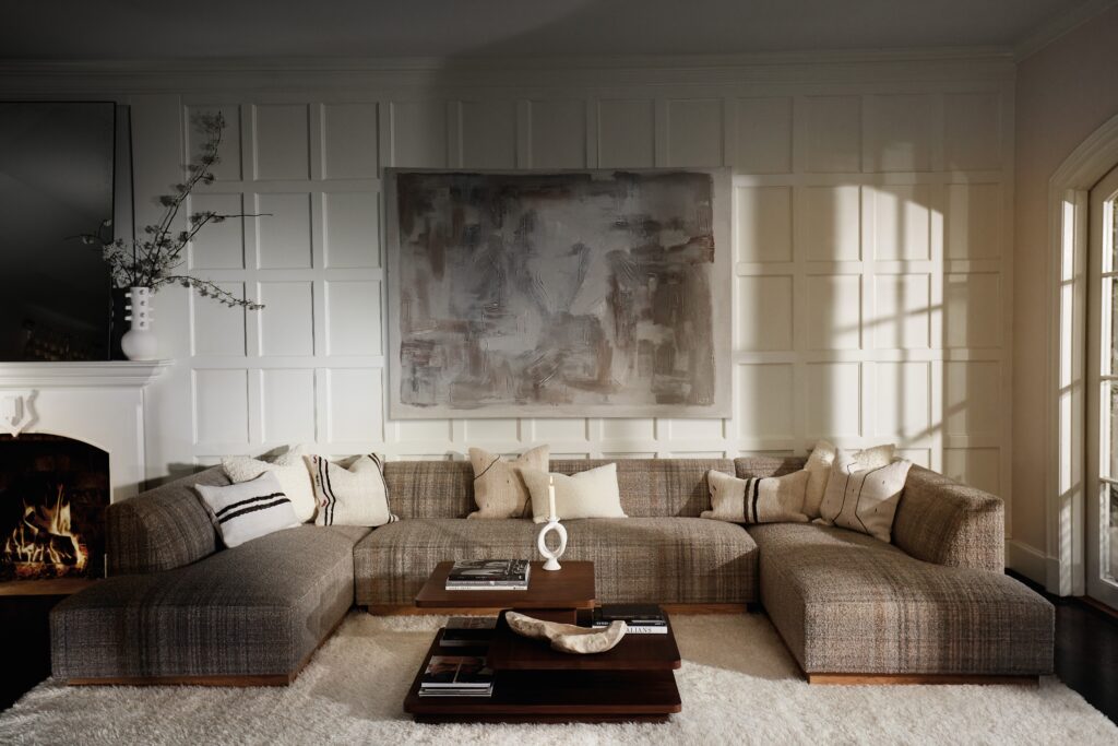 A dark living room with a neutral couch and dark coffee table all on a beige carpet.