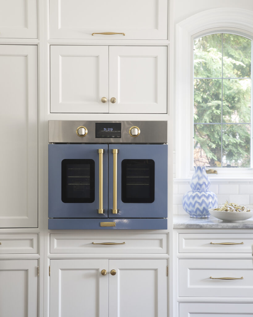 A white cabinet with a blue oven built into it with gold embellishments.