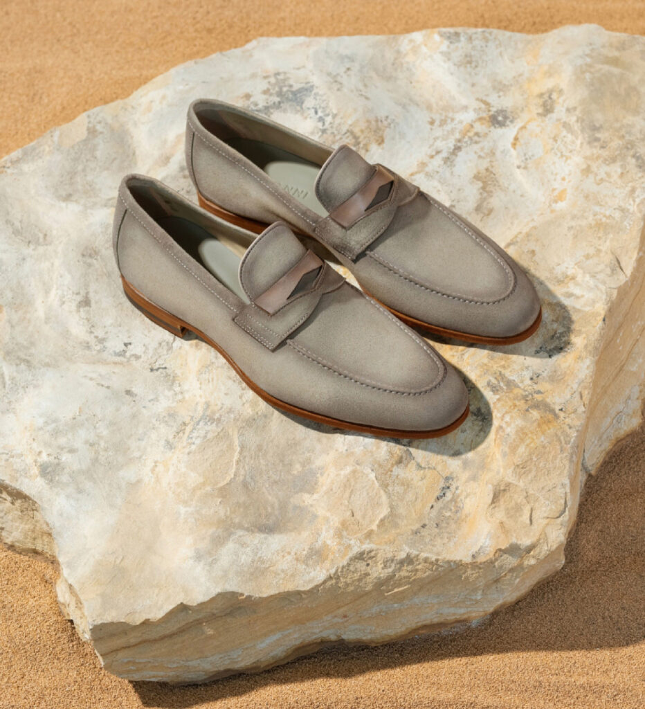 A pair of grey toned shows sit on a rock on top of a yellow background.