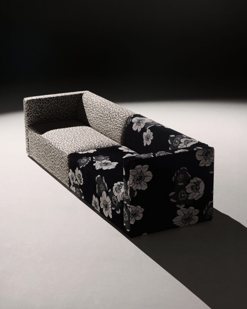 A half grey half black and white flower patterned couch in dramatic lighting.