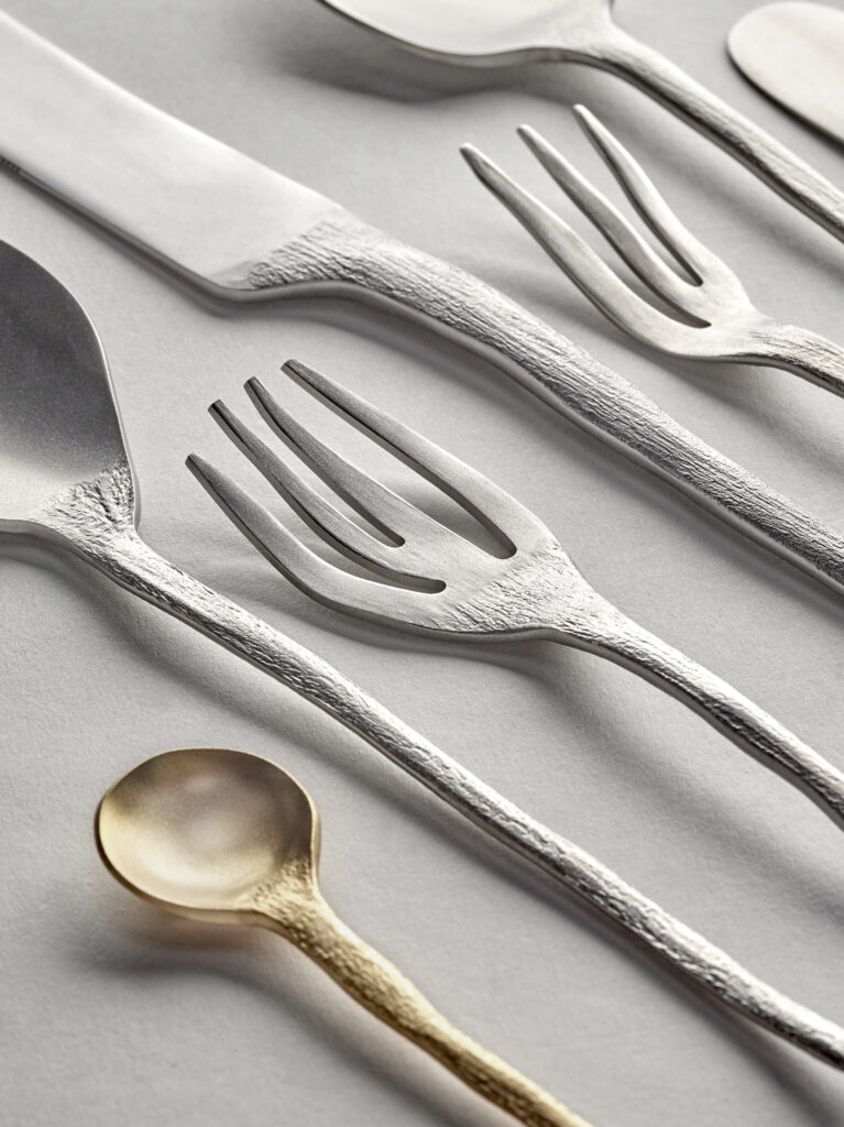 A set of silverware with a gold tiny spoon at the bottom of the photo.