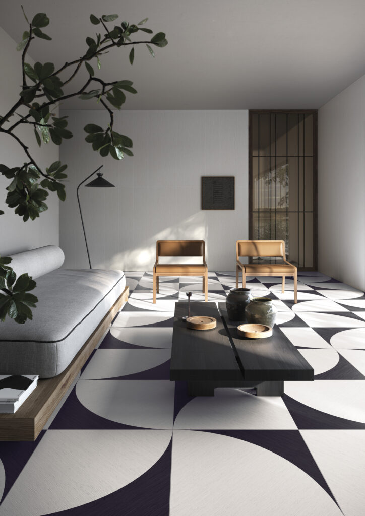 A living room with a bold flower black and white pattern hardwood floor with furniture set on it.