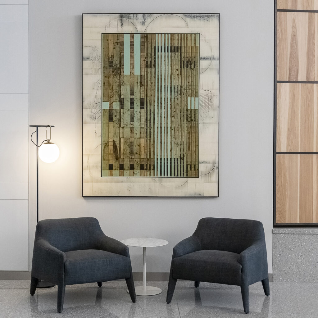 A dark green and mineral colored painting sits above two dark chairs in a living area.