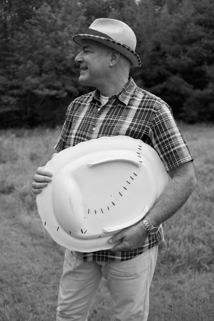 A black and white photo of a man outside holding a white dish at his side.