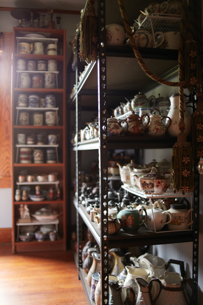 A collection of teapots on a tall shelf.