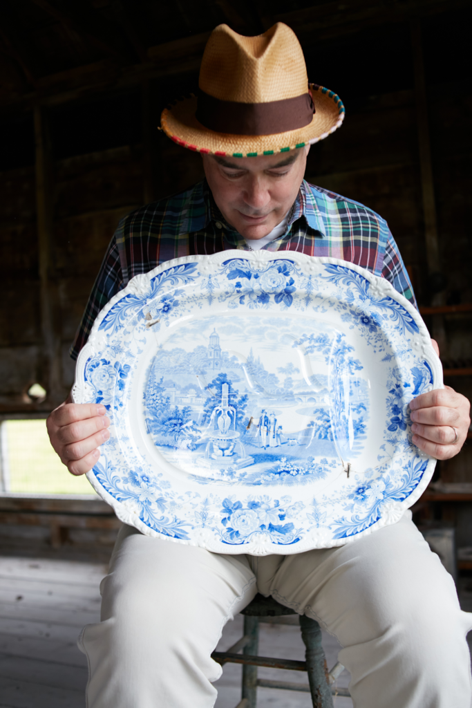 A man in a flannel shows a white dish with blue illustrations.