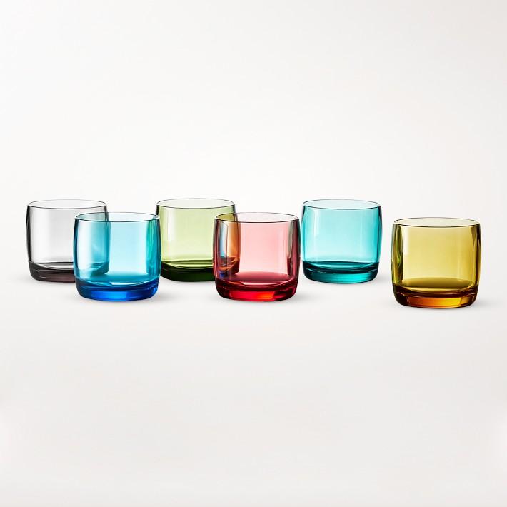 A selection of 6 opaque but colored glasses for tableware outdoors in colors black, blue, red, teal, yellow, and green against a white backdrop.