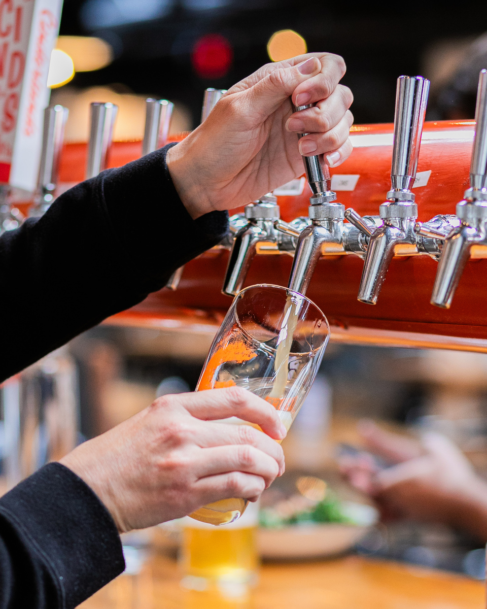 A person pours a glass of beer from the draft at Pittsburgh breweries.