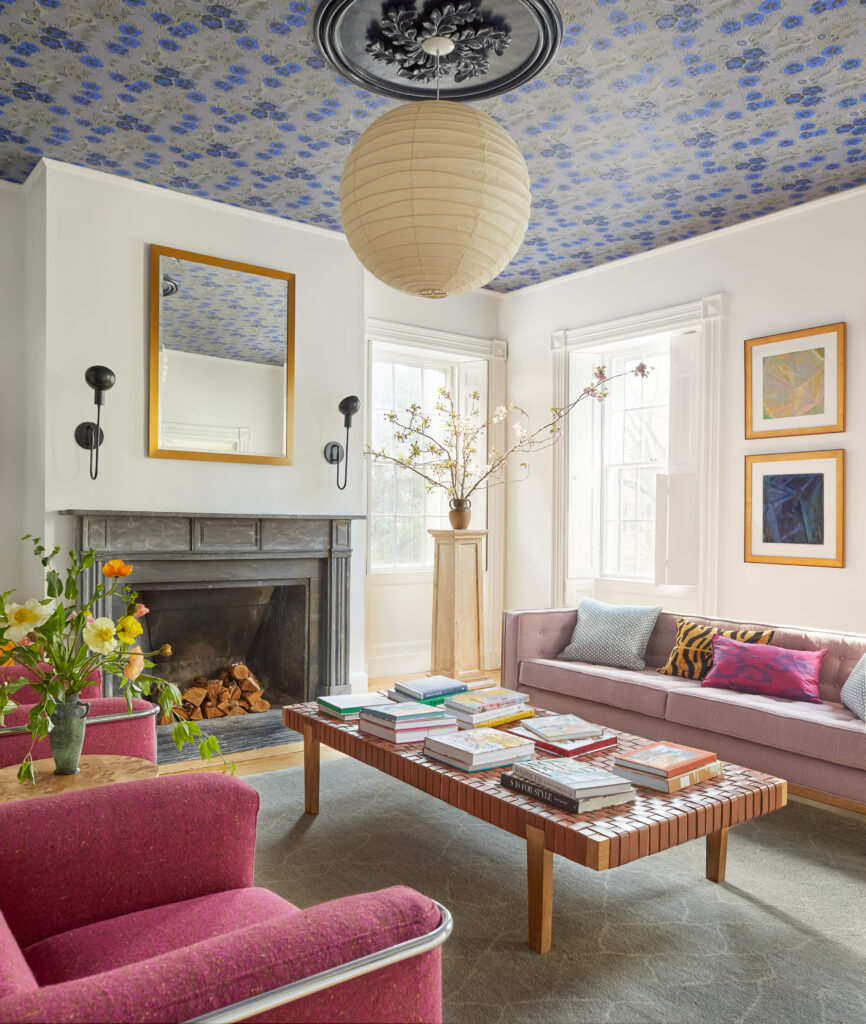An interior of a living room with pink couches, colorful ceilings, and a paper lamp in the center of the ceiling.