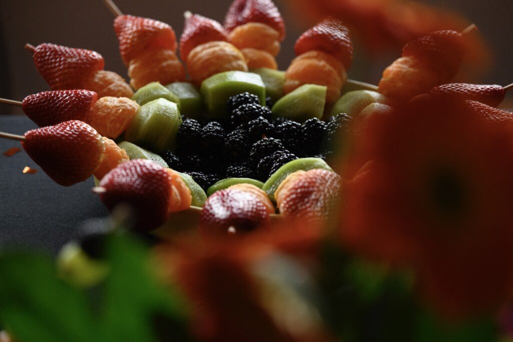 A close up shot of fruit skewers showing berries, grapes, oranges, and strawberries.