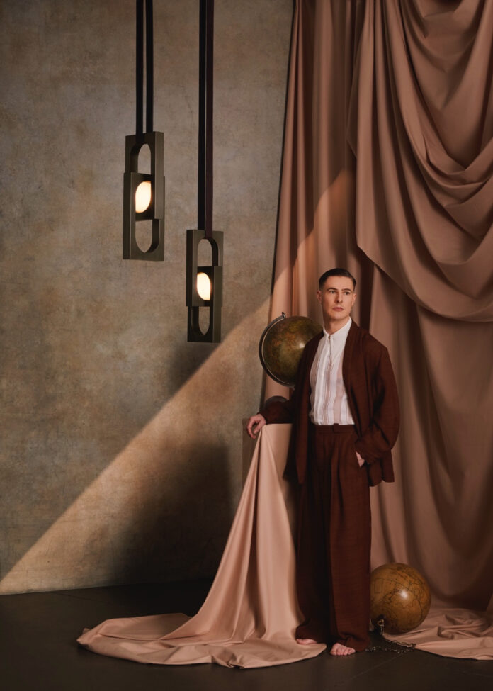 Designer Lee Broom in a room beside his lamp in his studio.