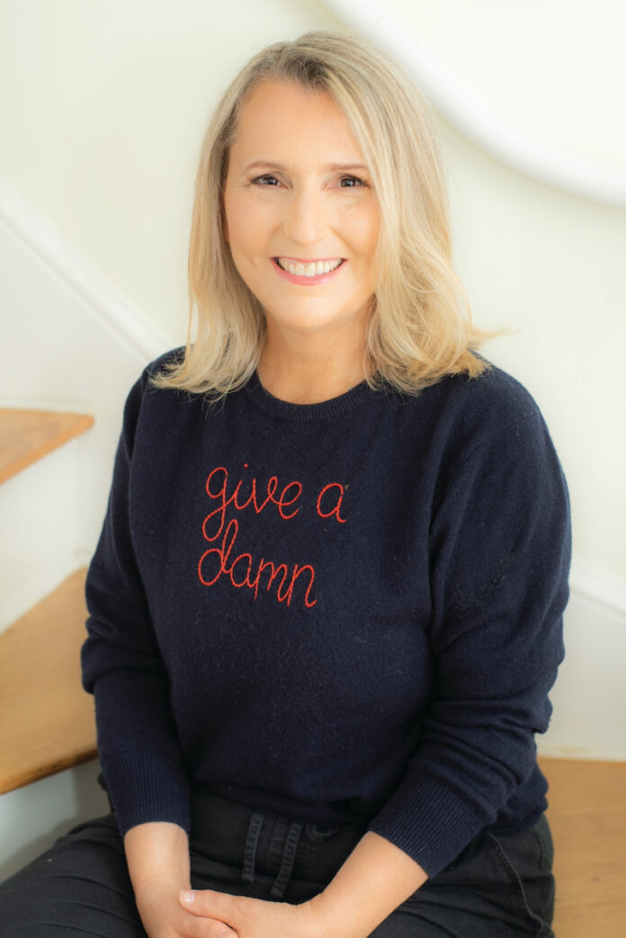 A blonde woman on a white background with a shirt reading 