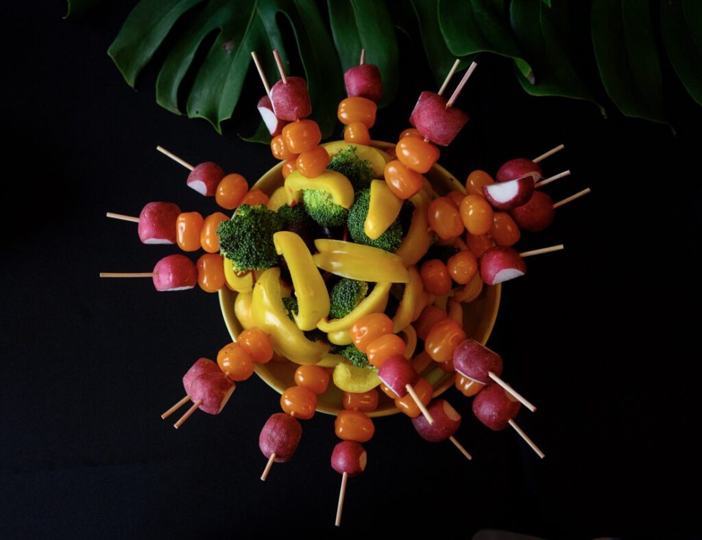 A ring of vegetable skewers with radishes, peppers, and broccoli stacked on each skewer.