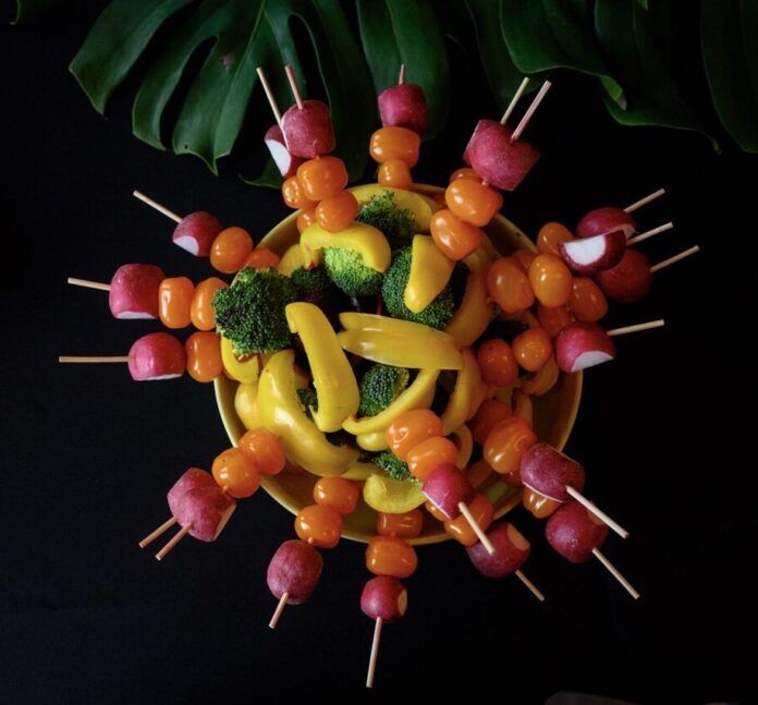 A ring of vegetable skewers with radishes, peppers, and broccoli stacked on each skewer.