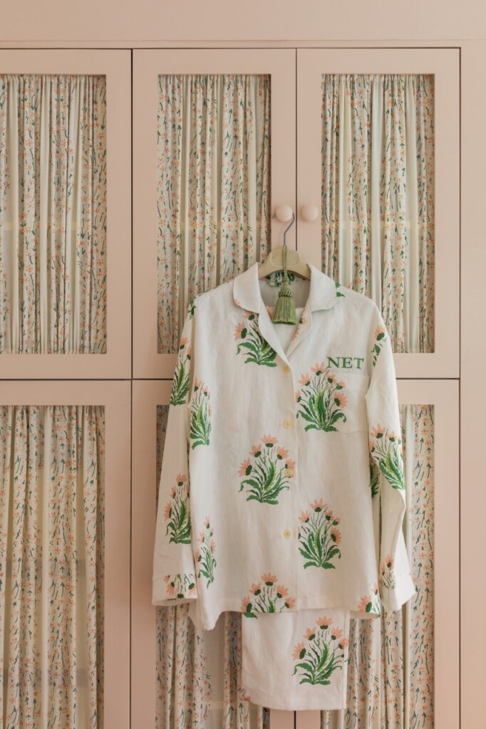 A white and green printed outfit of a jacket and pants sits behind a wood wall design by Nathan Turner.