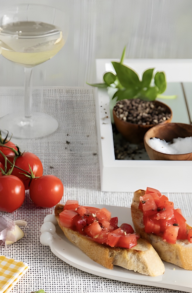 Bruschetta on a plate beside some heirloom tomatoes