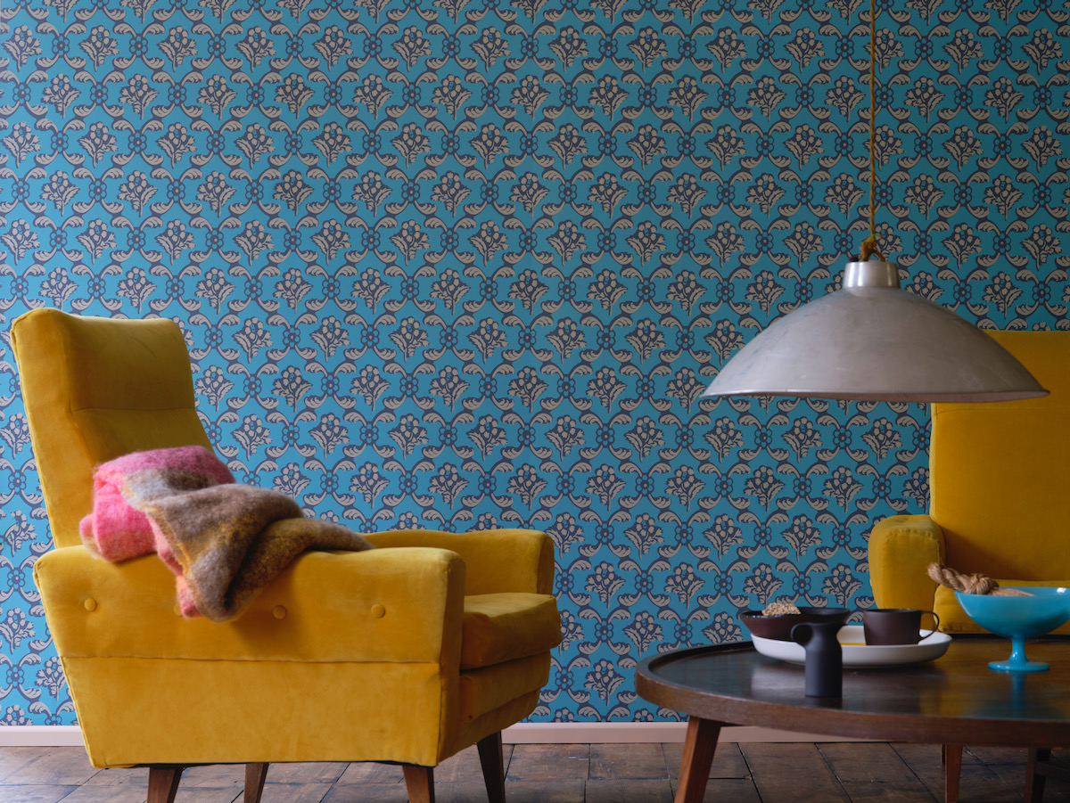 An intricate gem town wallpaper with a beige chair and a white standing lamp