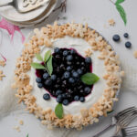 A summer berry recipe for a blueberry lemon cream pie plated on a white marble table
