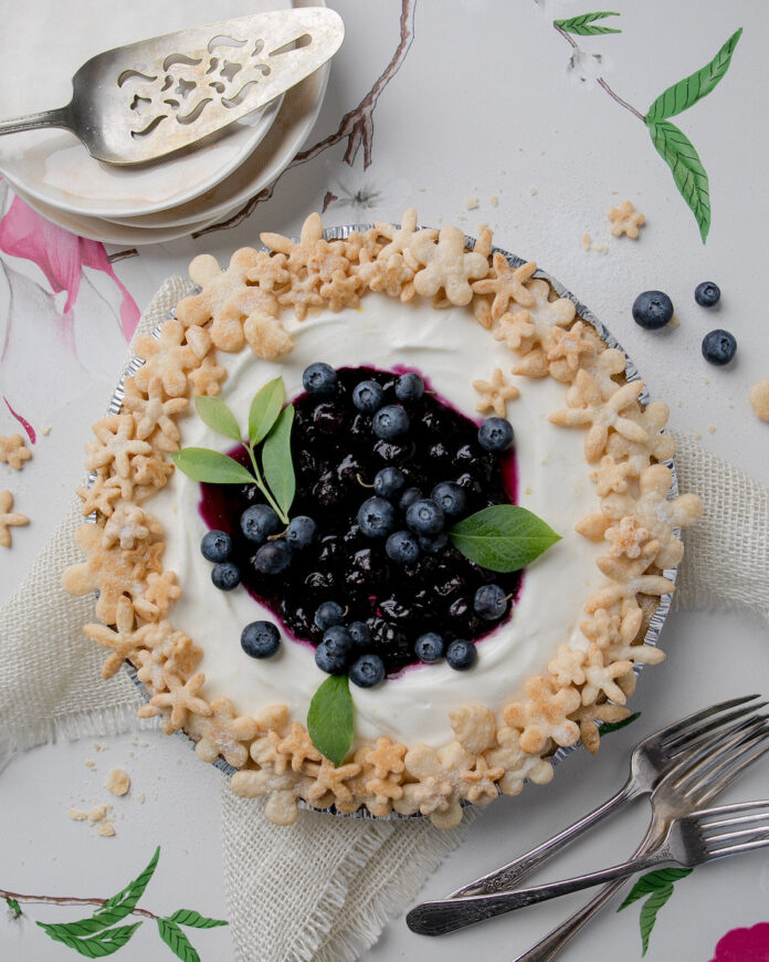 A summer berry recipe for a blueberry lemon cream pie plated on a white marble table
