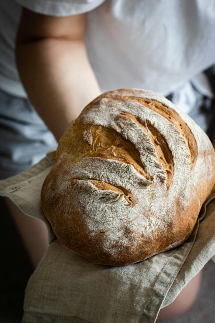TABLE Magazine Bread Tips A large loaf of bread in a baker's hands
