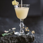 A chamomile cocktail, a pale yellow color, on a black background