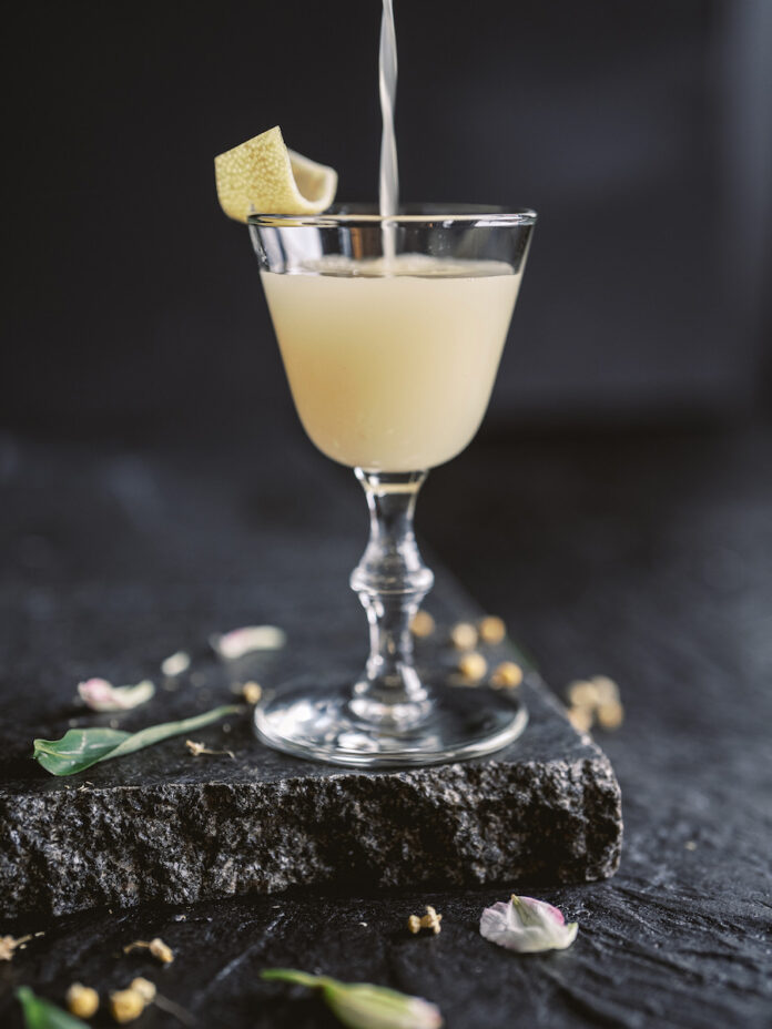 A chamomile cocktail, a pale yellow color, on a black background