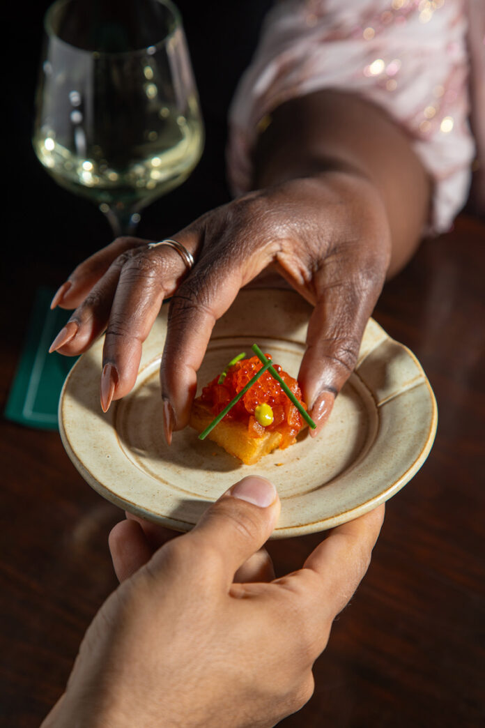 Two hands at work on a dish at Dakar NOLA