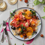 A plated BLT salad with large red heirloom tomatoes in it on a white background