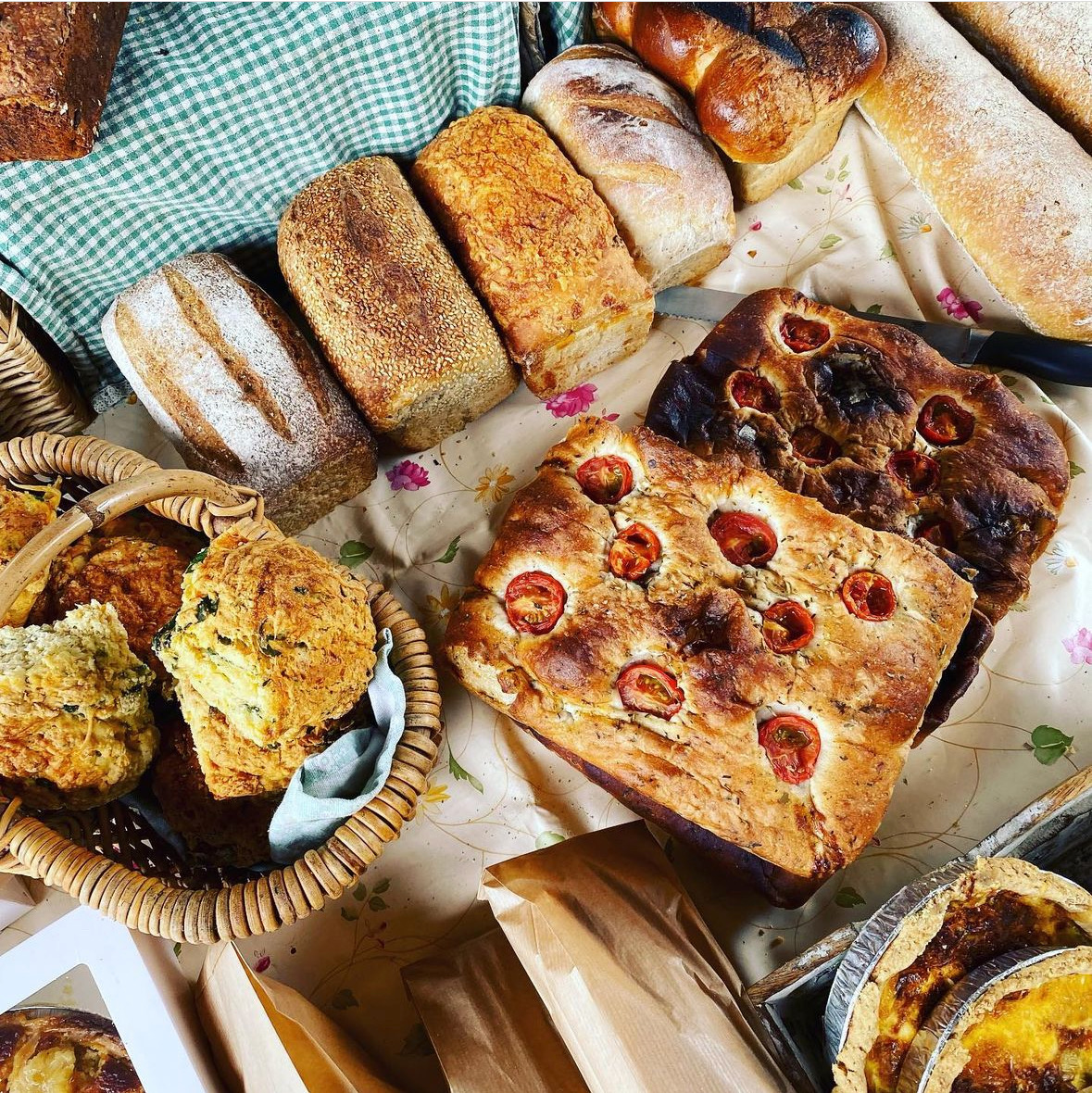 Several kinds of fruit-stuffed breakfast pastries on a Gingham tablecloth spread
