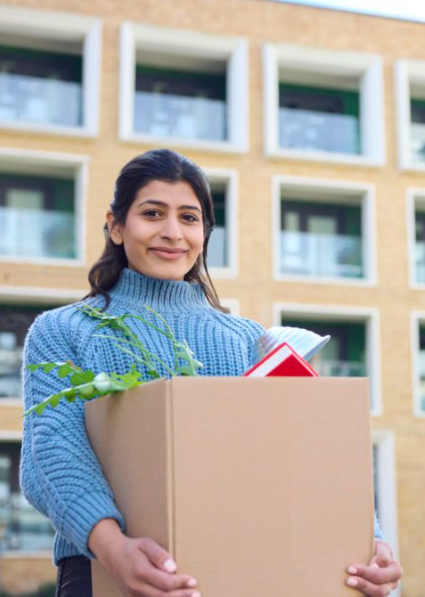 A young female college student holding a box of dorm essentials