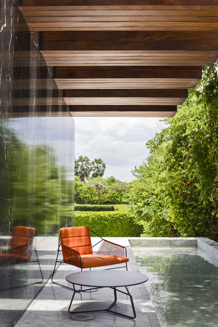 TABLE Magazine Oasiq 4 A red chair on a porch deck overlooking a scenic, lush view