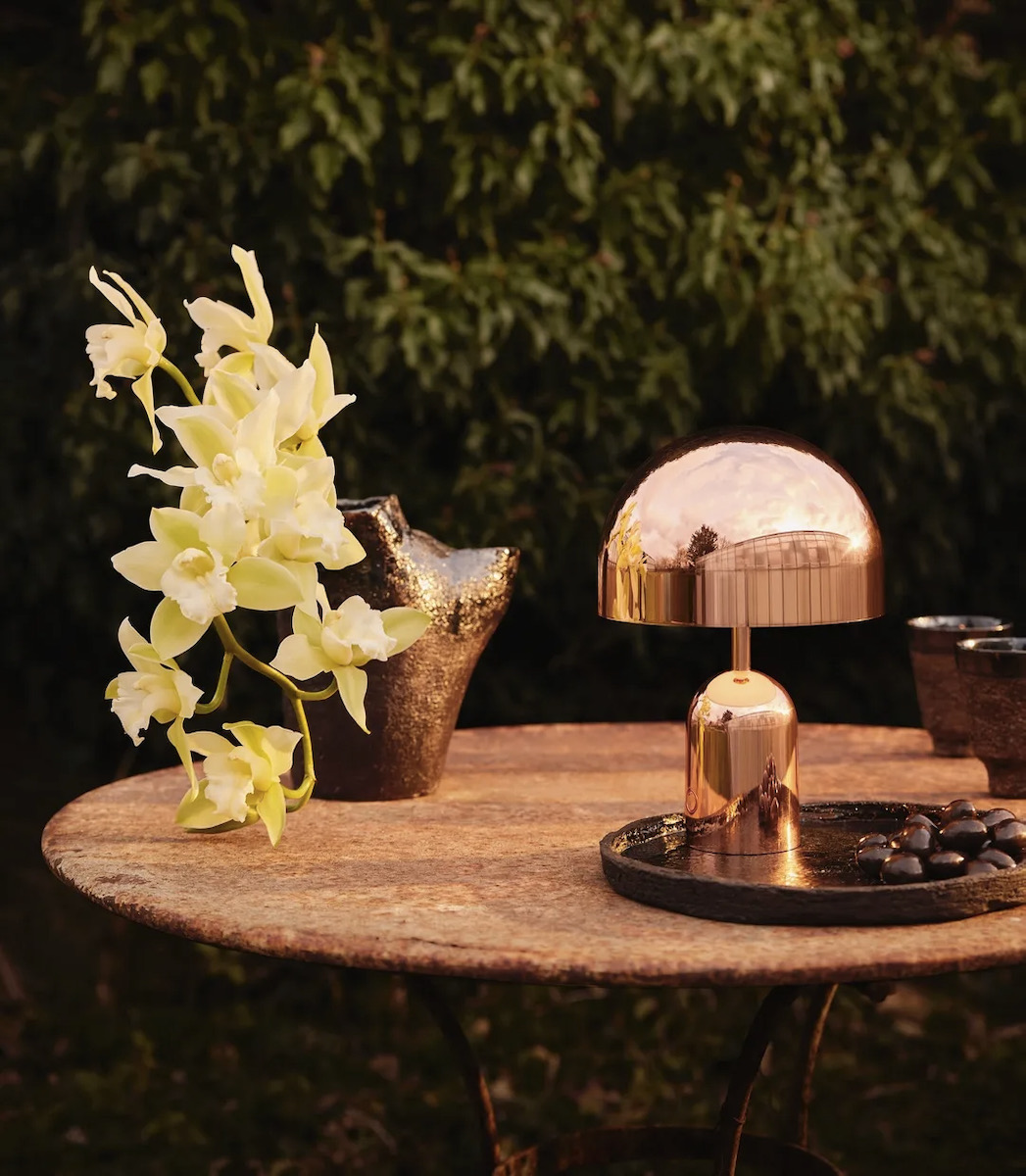 A staged lamp on a wooden table with white flowers beside it 